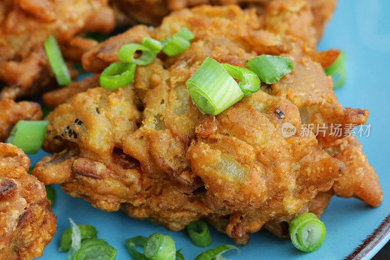 全帧图像的自制脆洋葱bhajis / pakoras装饰着切碎的葱，在一个绿松石盘子上，印度菜素食小吃，高架的视野，聚焦前景